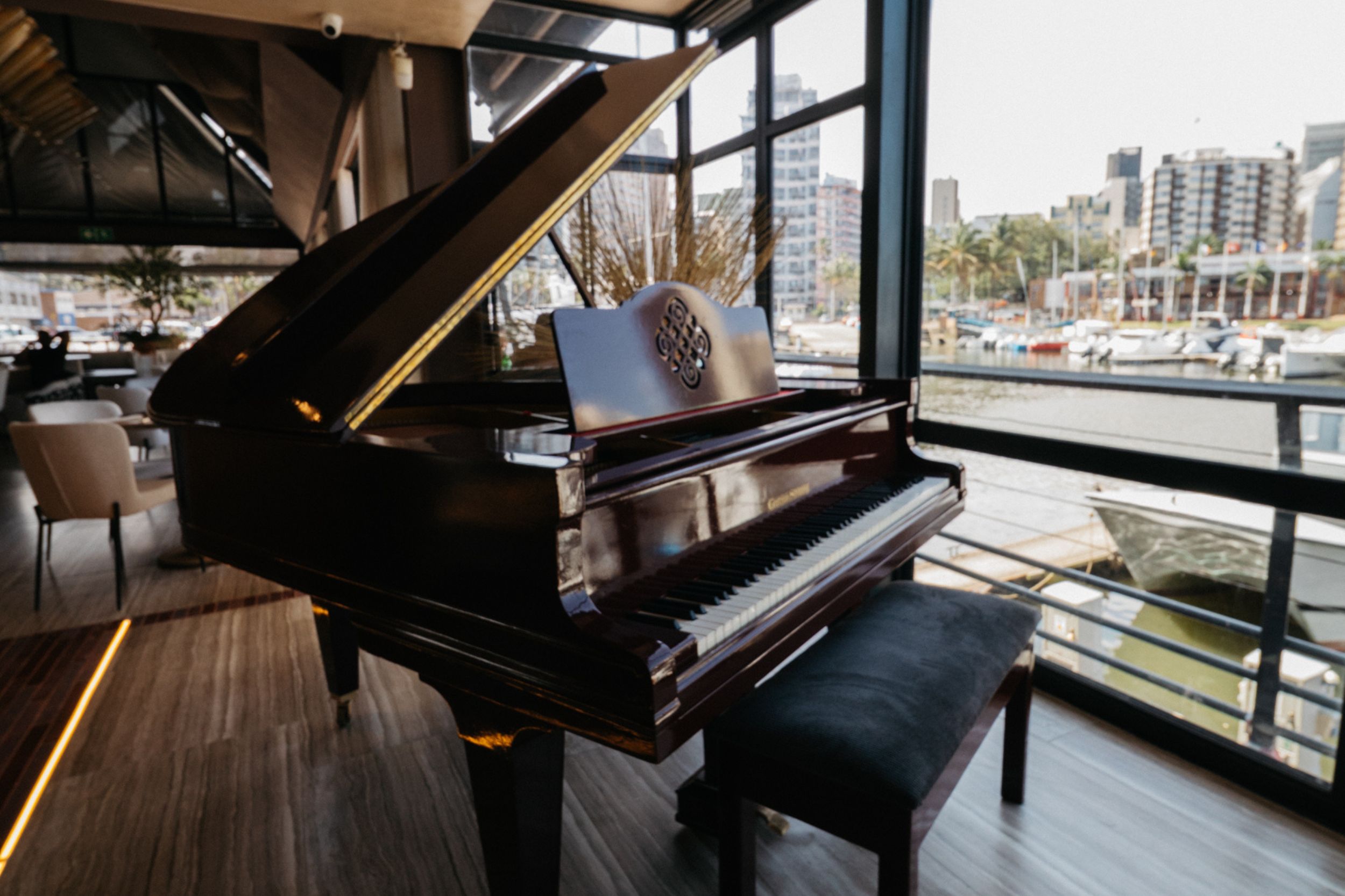 The upstairs cocktail lounge, with bay views and a baby grand piano, suited to sundowners and standing receptions.